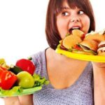 ragazza che si abbuffa di fronte a abbondanza di cibo