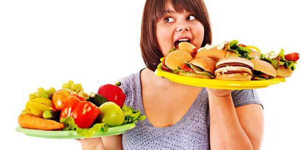 ragazza che si abbuffa di fronte a abbondanza di cibo